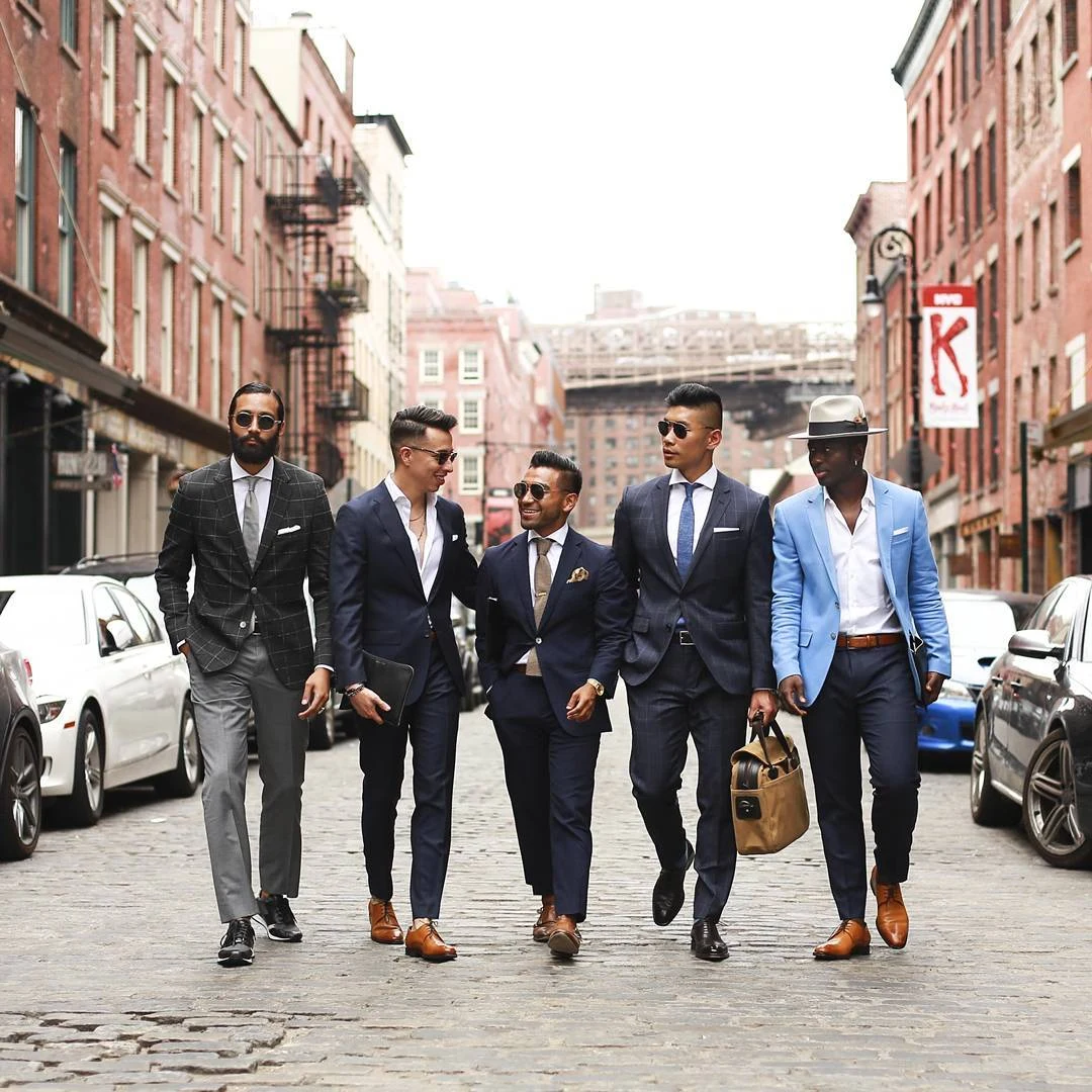 A group of men in tailored suits walking along a New York street