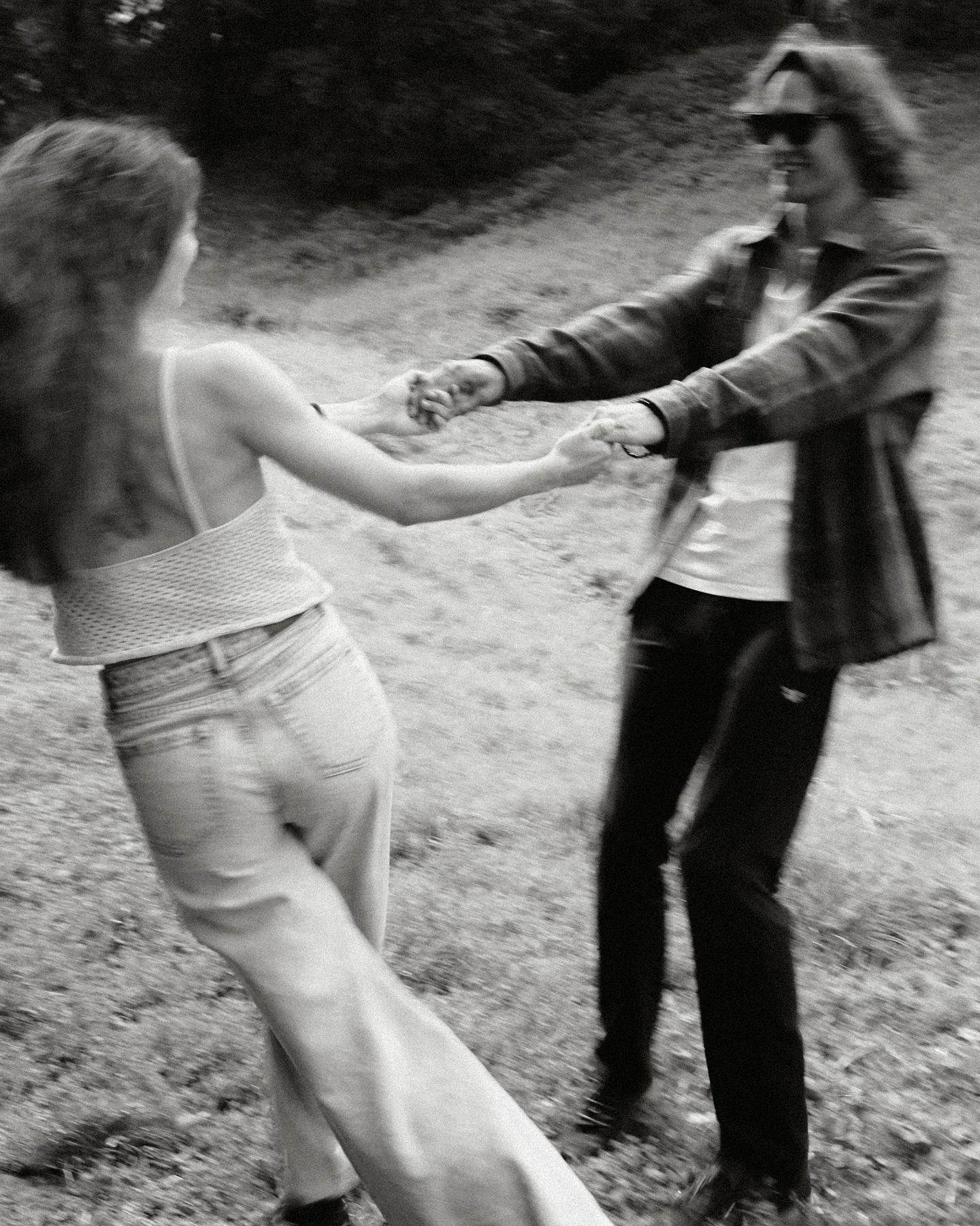 A couple playfully holding hands outdoors, in black and white