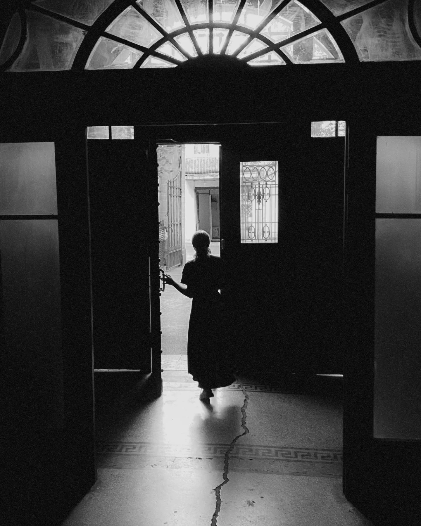 A silhouette framed by a tall arched doorway in black and white