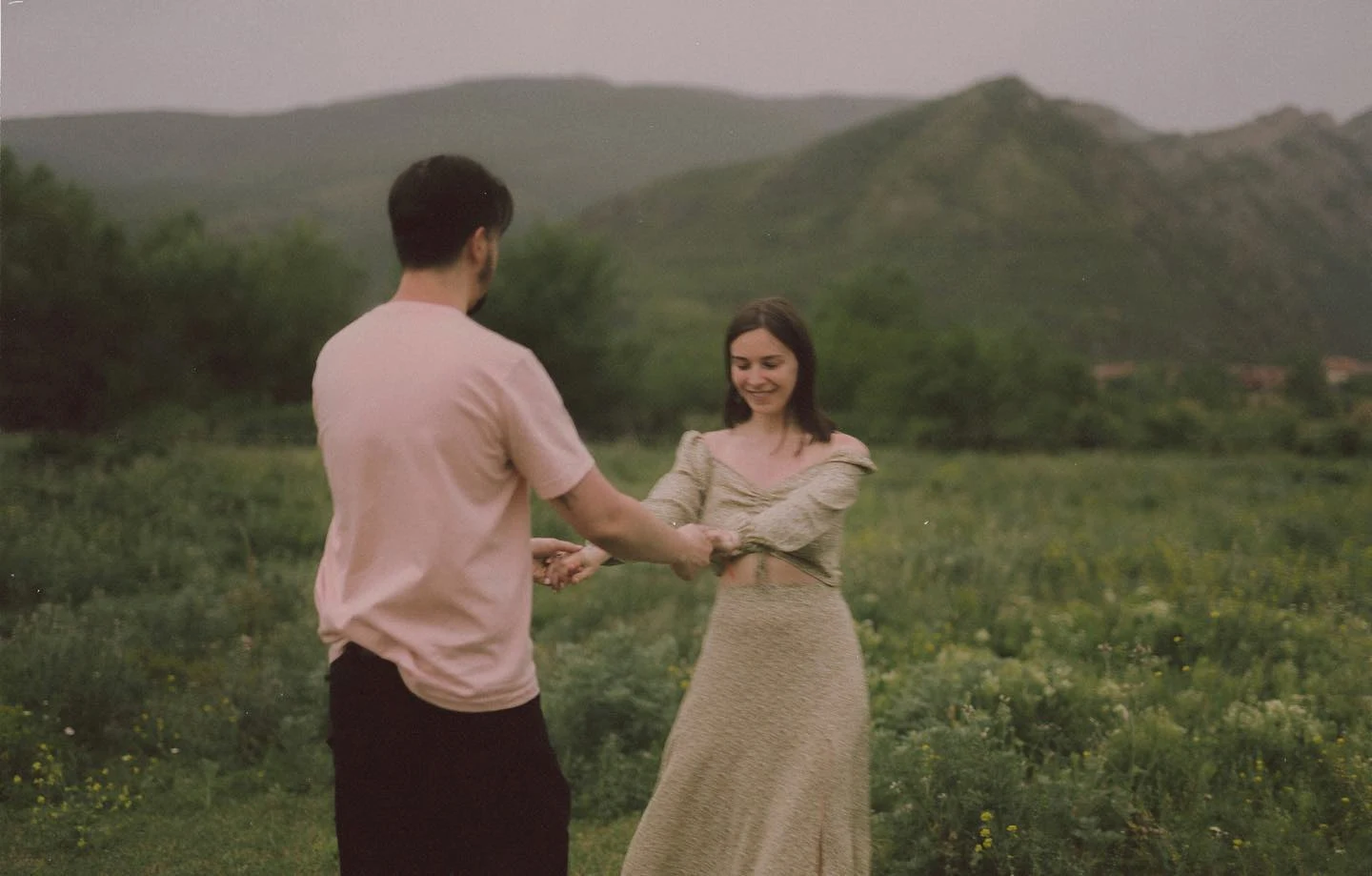 A couple holding hands in a green mountain landscape