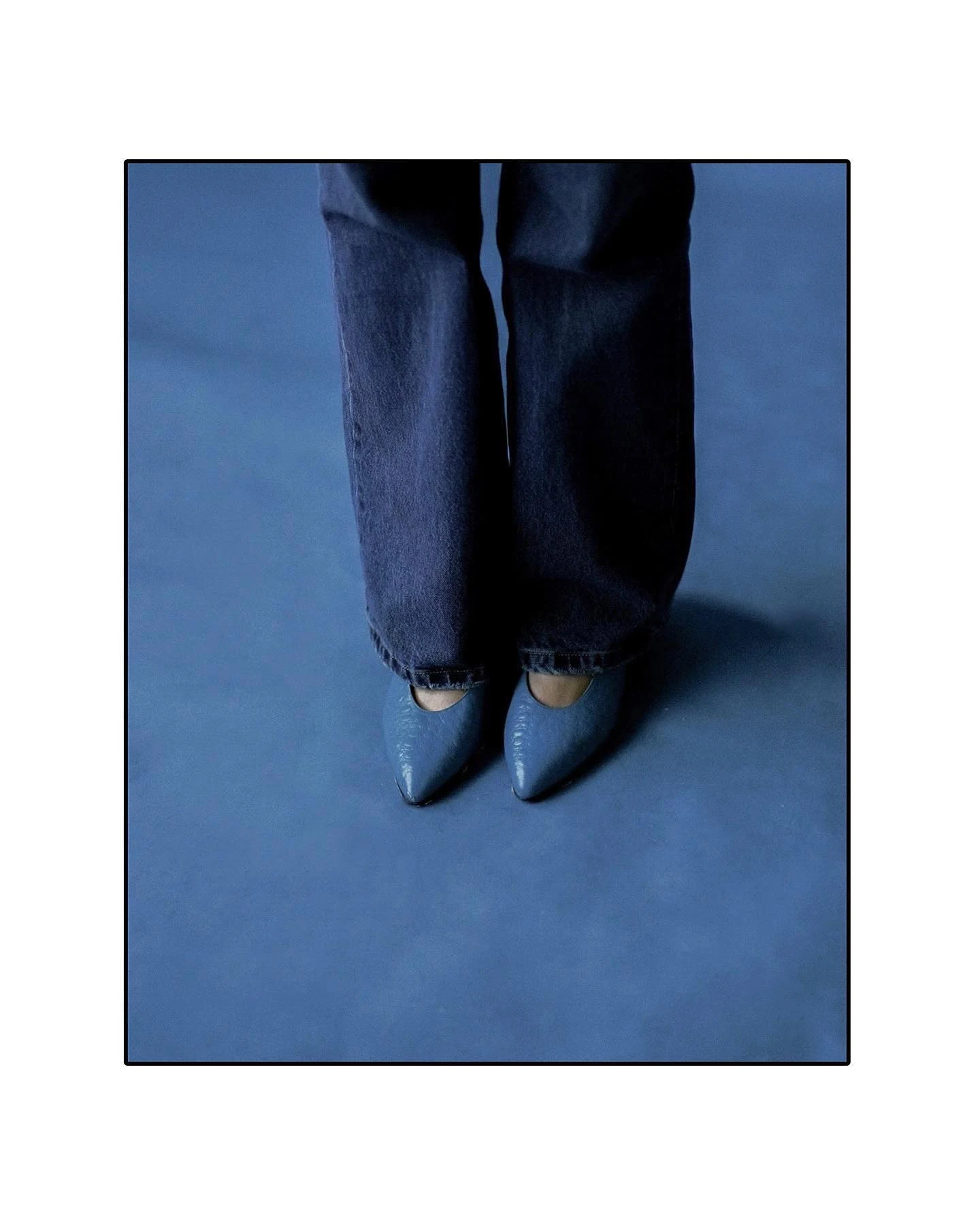 Blue tailored trousers and pointed shoes against a blue background
